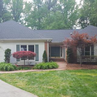 A charming suburban house surrounded by well-maintained landscaping and trees.