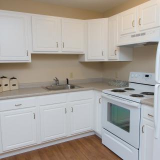 A modern kitchen with white cabinets, a stove, oven, and sink.