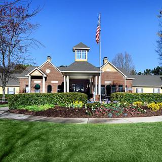 A well-landscaped building with a flagpole and neatly maintained flowers and grass.