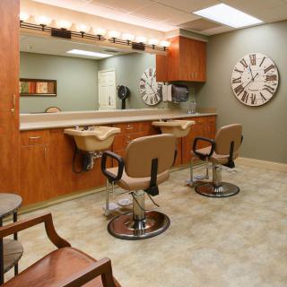 A well-lit hair salon interior with multiple barber chairs and large mirrors.