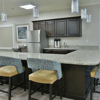 A modern kitchen featuring a spacious countertop with bar stools and sleek appliances.