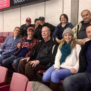 A group of people smiling while seated indoors, dressed in casual winter clothing.