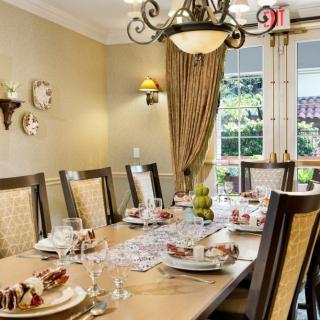 An elegantly set dining room with a chandelier and formal dinner setting.