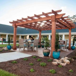 A pergola with outdoor seating surrounded by a landscaped garden area.