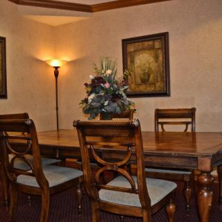 A cozy dining room featuring a wooden table with matching chairs, soft lighting from a floor lamp, and decorative artwork on the walls.