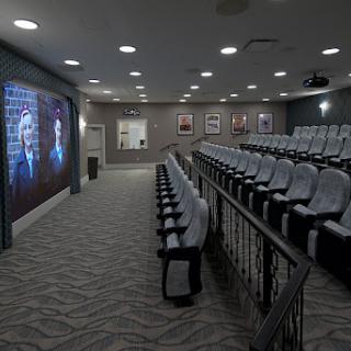 A modern auditorium equipped with comfortable seating and a large projector screen for presentations.