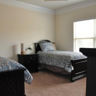 A minimalist bedroom with twin beds and a nightstand next to a window.