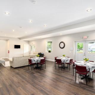 A modern dining area with neatly arranged tables and chairs, illuminated by natural light.