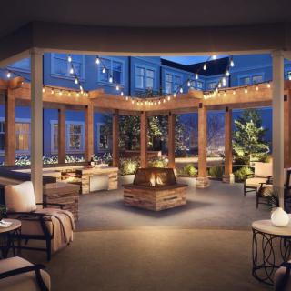 A cozy outdoor patio with a central fireplace and string lights illuminating the evening ambiance.