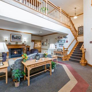 A cozy living room interior featuring a fireplace, comfortable seating, a staircase, and decorative elements.
