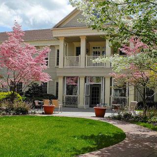 A beautiful spring day showcasing a charming house surrounded by blooming flowers and lush green grass.