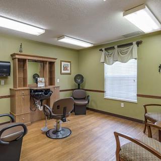 A cozy hair salon with chairs, a mirror, and a hairdryer in a well-lit room.