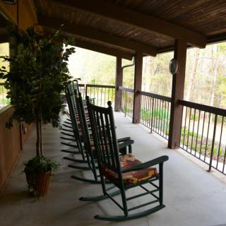 A peaceful porch with a row of rocking chairs overlooking nature.