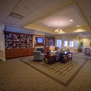 A cozy living room interior with bookshelves, comfortable seating, and a television.
