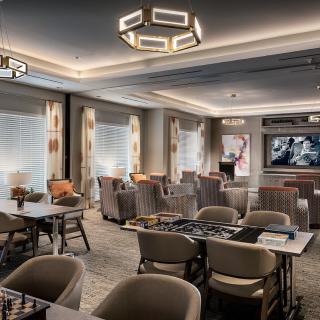 A modern lounge area with comfortable seating and a large television on the wall.