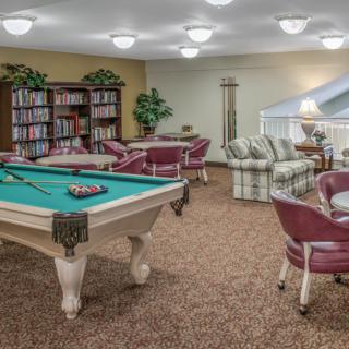A cozy game room featuring a pool table and a small library with comfortable seating.