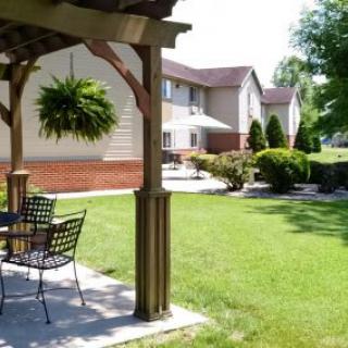 A backyard patio with furniture overlooking a well-maintained lawn and residential building.