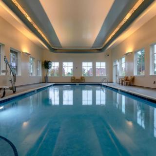 A serene indoor swimming pool with elegant lighting and large windows.