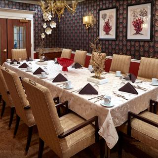 A formally set dining room with elegant decor, featuring a long table adorned with neatly arranged plates, cups, and napkins.