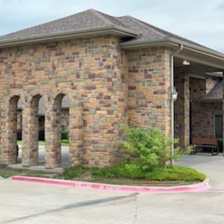 A beautifully designed stone building with a well-landscaped entrance.