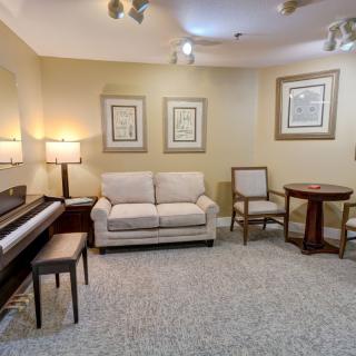 A cozy living room featuring a piano, comfortable seating, and wall art.