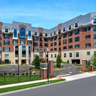A modern multi-story apartment building with a brick exterior and landscaped surroundings.