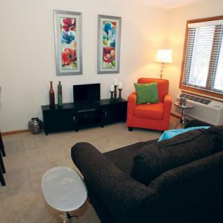 A cozy living room with modern decor, featuring a sofa, armchair, and a television.