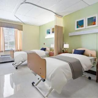 A bright and welcoming hospital patient room featuring two beds and modern decor.