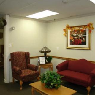 A cozy waiting room with a red armchair, couch, and decorative elements.