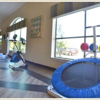 An indoor gym space equipped with a trampoline and other exercise equipment.