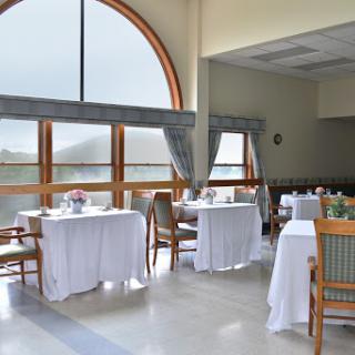 A serene dining area featuring elegantly set tables and large windows that invite natural light.