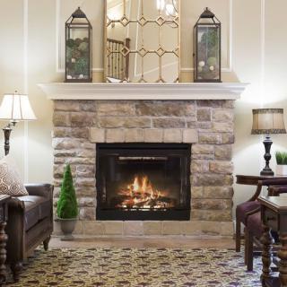 A cozy living room featuring a stone fireplace, elegant lamps, and classic decor.