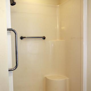 A simple bathroom shower with a towel and grab bar.