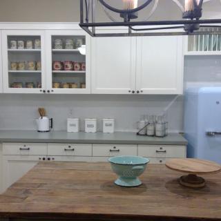 A modern kitchen with white cabinets, a wooden countertop, and organized decor.