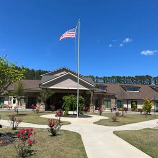 A building with a flagpole on a sunny day, surrounded by landscaped paths and plants.