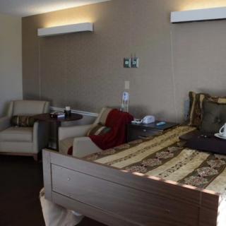 A hospital room with a bed, chairs, and medical equipment.