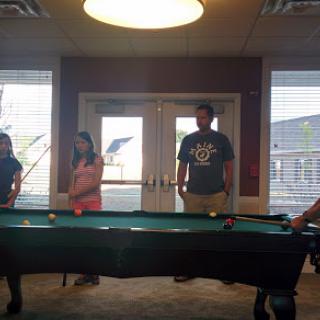 A group of friends enjoying a game around a pool table.
