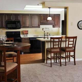 A modern open-concept kitchen with wooden cabinets and a dining area featuring bar stools.