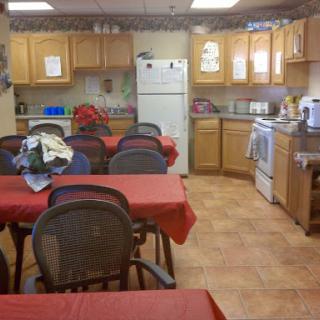 A cozy kitchen and dining area with wooden cabinets and tables set for a meal.