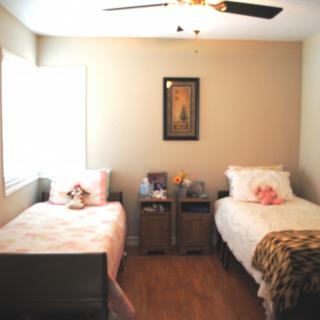 A cozy bedroom featuring two twin beds with soft bedding and a central piece of artwork on the wall.