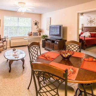 A bright and cozy living room with an adjoining dining area, featuring elegant furniture and a warm color palette.