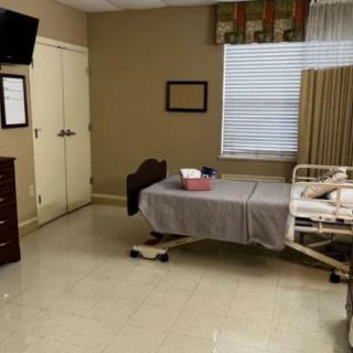 A hospital room featuring a single bed, a television, and basic furnishings.