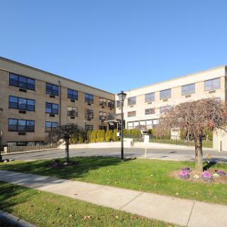 A view of a modern multi-story building with landscaped grounds and clear blue skies.