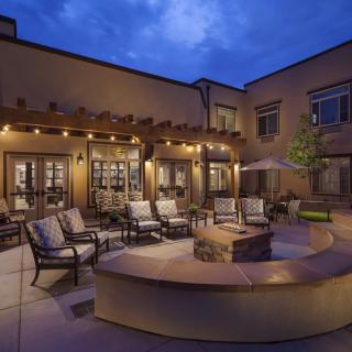 A cozy outdoor patio with a fire pit and comfortable seating, beautifully lit in the evening.