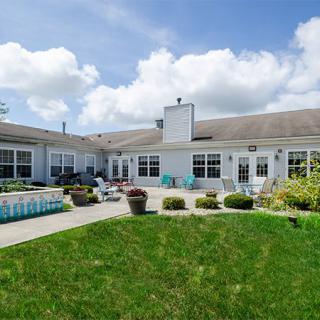 A spacious backyard with a patio and well-maintained lawn under a partly cloudy sky.