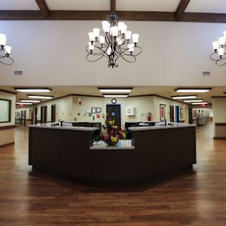 A spacious and elegantly designed lobby featuring chandeliers and wooden flooring.