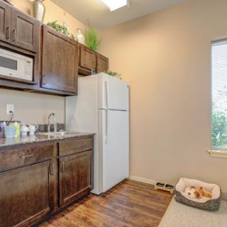 A cozy kitchen featuring modern wood cabinets, a white refrigerator, and ample natural light.