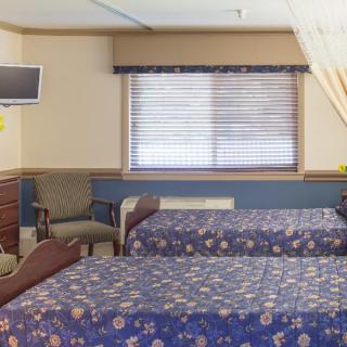 A hospital room with two patient beds, a television, and comfortable seating.