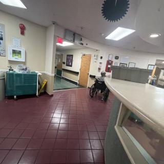 A view of a hospital corridor with a wheelchair near the reception area.