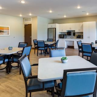 A modern dining area with tables and chairs, adjacent to a kitchen.